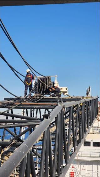 Technicians maintaining a marine crane boom